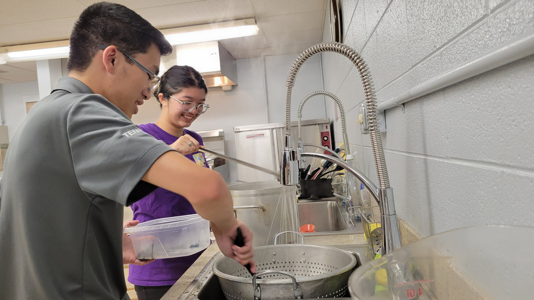 Two students at a sink filling up a pot of water