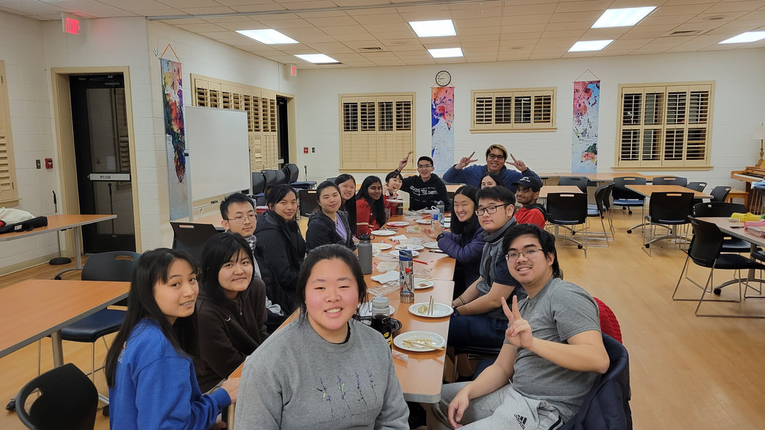 A group of students smiling at the camera and plates of dumplings on the table